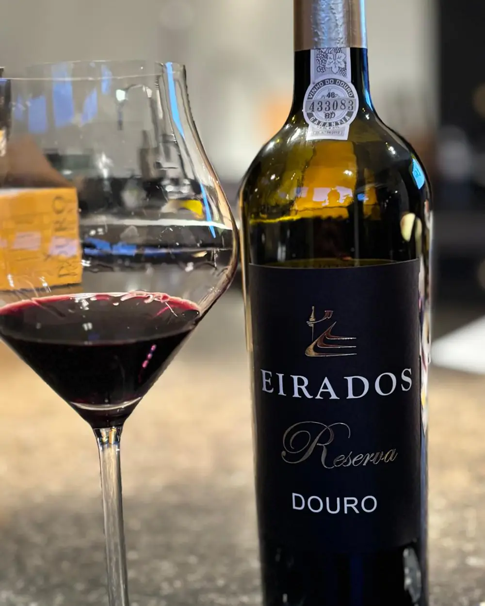 Een fles Eirados Reserva naast een ingeschonken glas rode wijn.